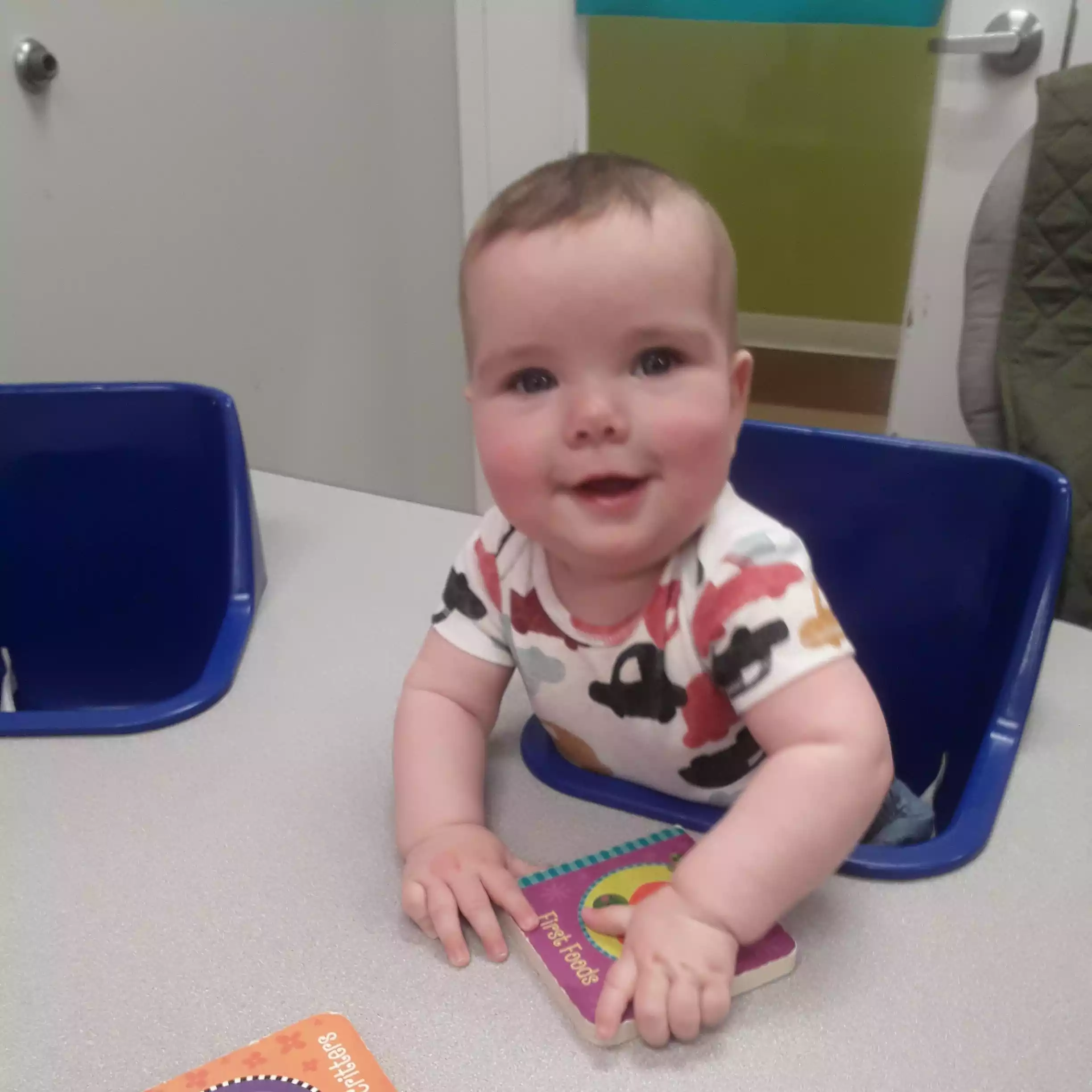 Infant Reading Board Books at the Activity Table Baby sitting at table with board books in infant program