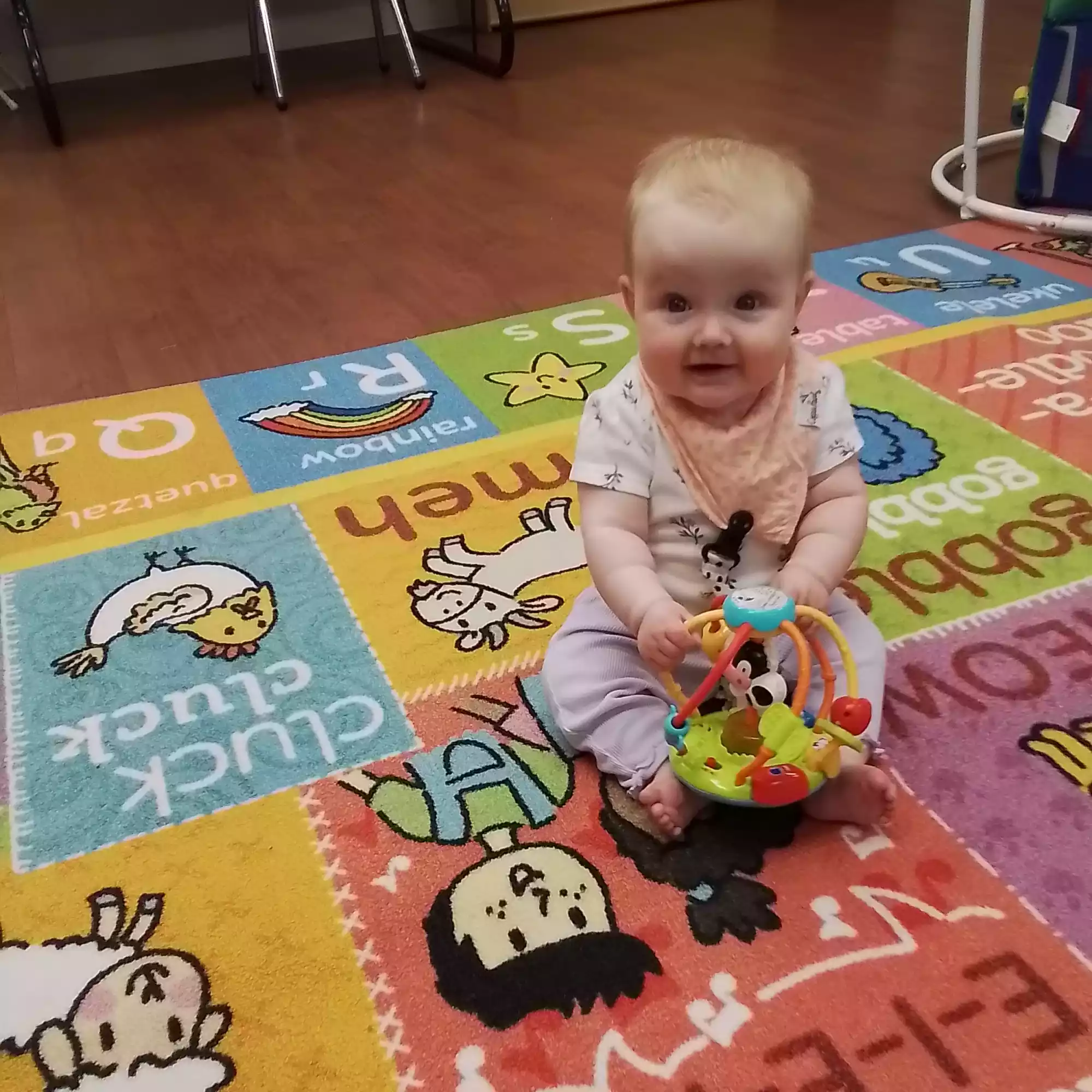 Infant Sitting on Play Mat Exploring Activity Rattle Baby sitting on colorful play mat with interactive sensory rattle in infant program