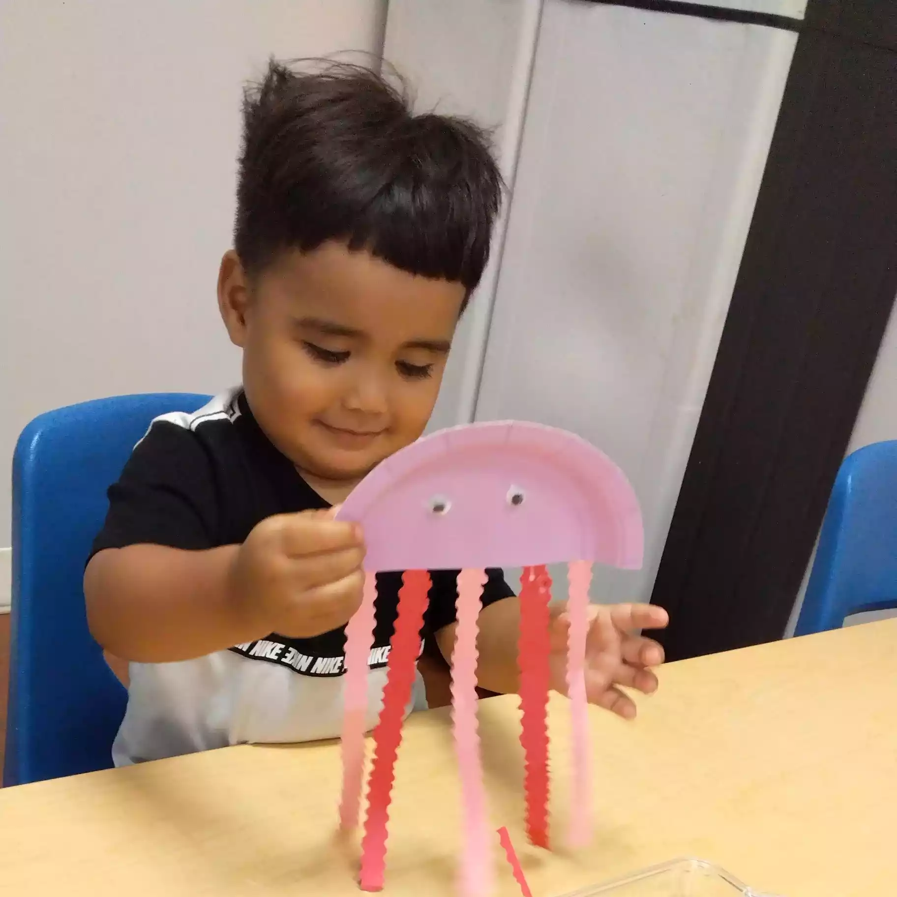 Pinebrook Pre-K Student Displaying Finished Paper Jellyfish Craf Child showing completed paper jellyfish craft at Pinebrook Montessori